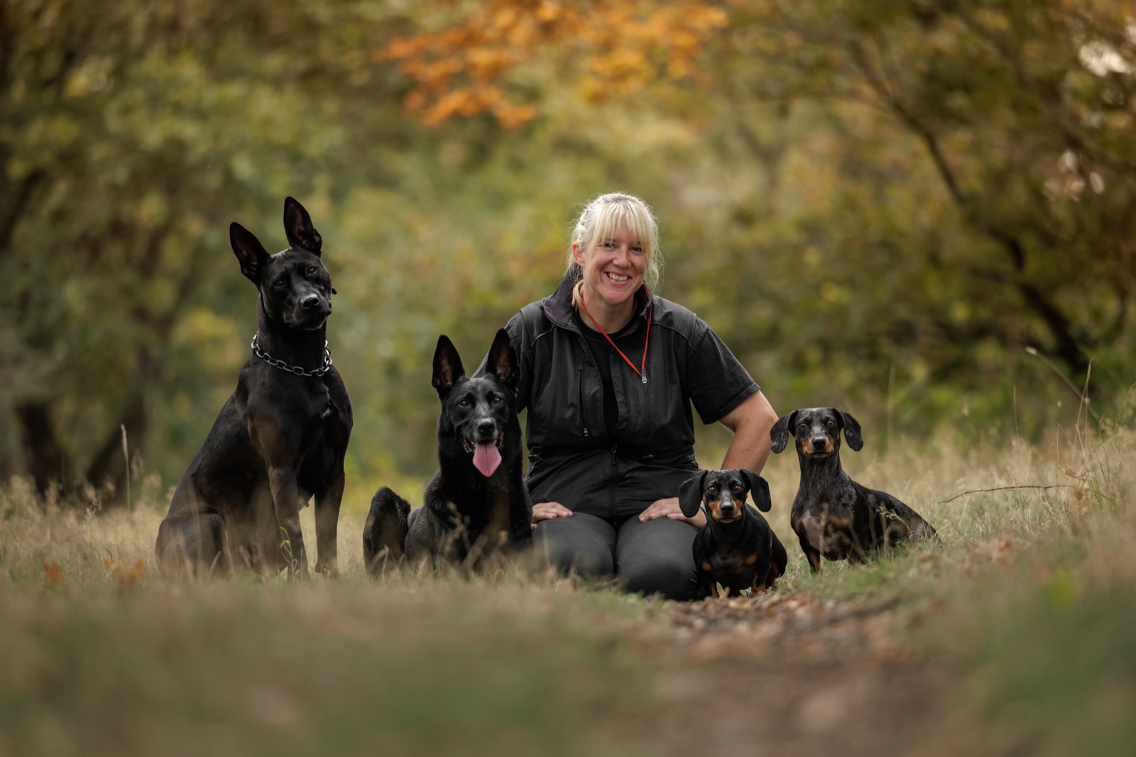 Jamie sitting on a woodland path with Nyx, Dante, Lyra and Lexi